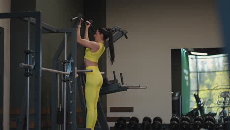 Hispanic-Woman-Does-Pull-Ups-On-Gravitron-For-Strengthening-The-Shoulder-Muscles-In-The-Gym.-A-woman-does-the-exercises-correctly-pulling-up-with-a-straight-back.-pull-ups-on-the-simulator